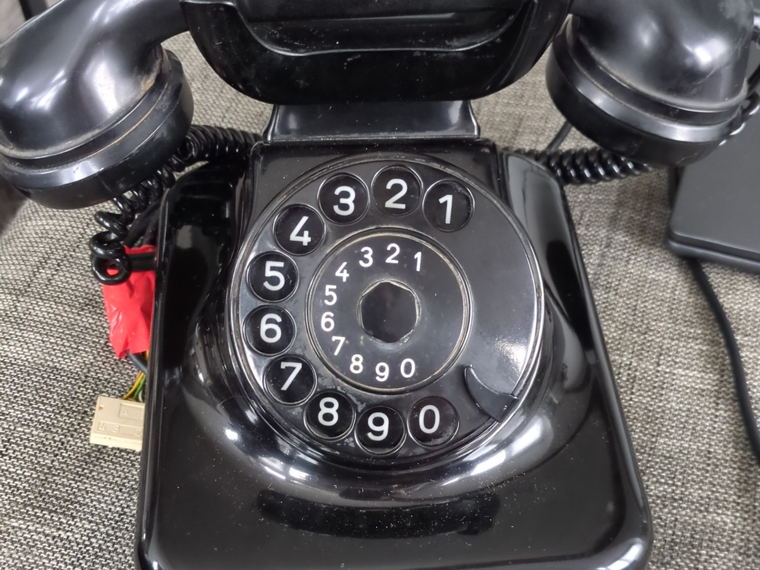 A black bakelite rotary desk telephone, intact, seen from above with its numbered dial and handset.